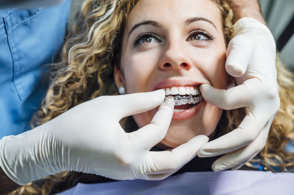 Doctor putting a clear dental aligner to the patient woman. Retainer After Braces